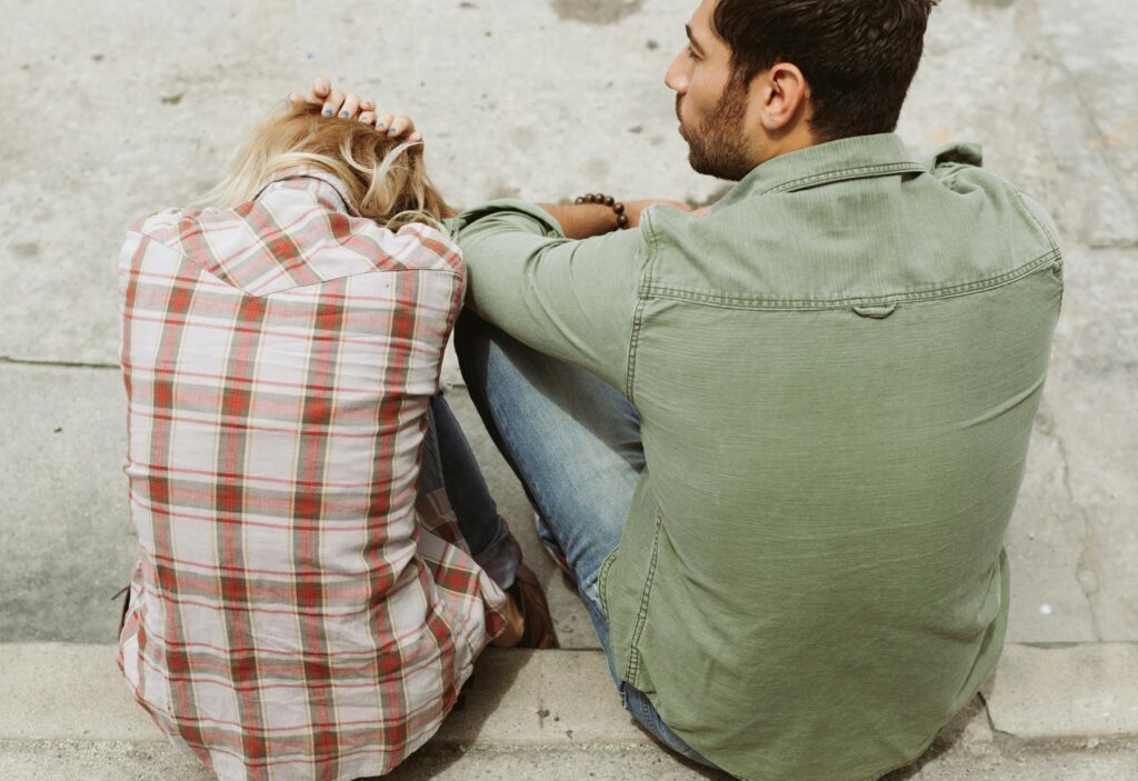 Couple sitting outside on concrete steps having a difficult conversation.They have paused to regulate their nervous system.