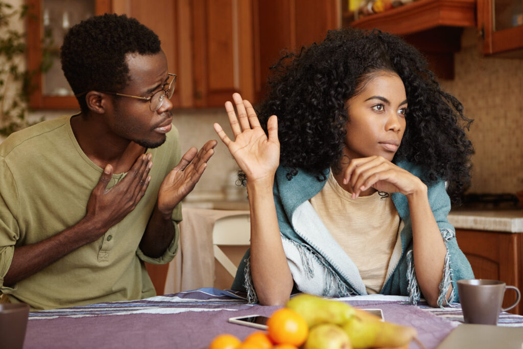 Man apologizing to woman who looks upset and withdrawn during a conflict at home.