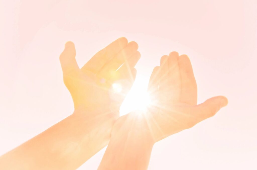 Hands reaching toward light representing readiness for deep healing and therapy intensives